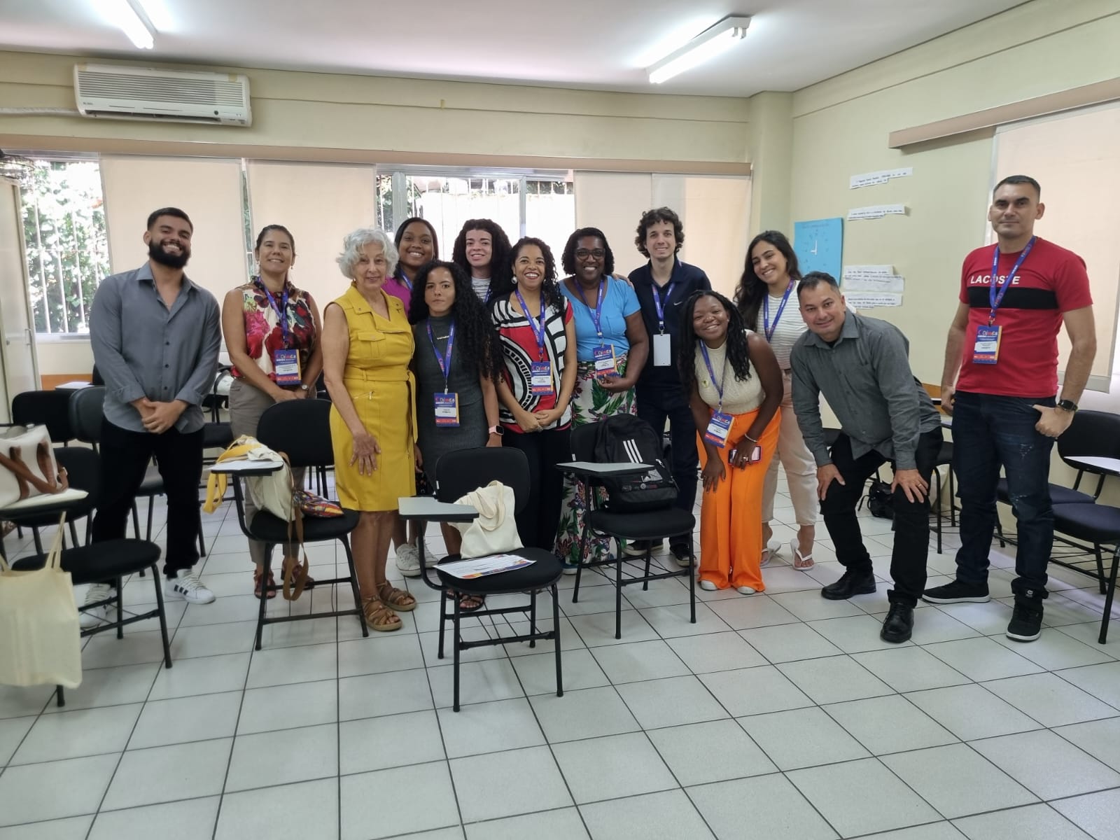 Treze pessoas perfiladas para foto na sala do minicurso. Piso claro, paredes claras,